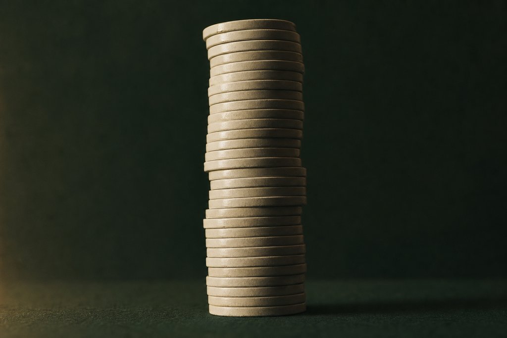 Sehr hoher Stapel unbedruckter Spielchips aus flachem Winkel vor dunkelgrünem Hintergrund